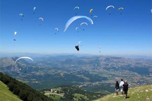 a group of people standing on a hill flying kites at GrappaLand in Crespano del Grappa