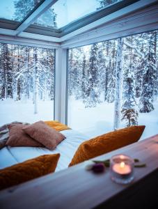 a bedroom with a window looking out at snow covered trees at Arctic Skylight Lodge in Äkäslompolo