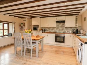 a kitchen with white cabinets and a wooden table and chairs at Owl's Nest in South Molton