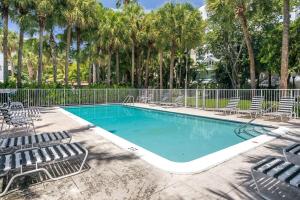 a swimming pool with chairs and a fence and palm trees at Selina Miami River in Miami
