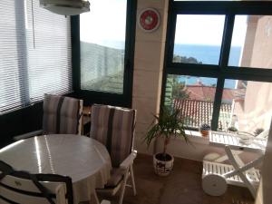 a dining room with a table and chairs and windows at Apartman Ćeran in Herceg-Novi