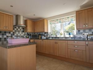 a large kitchen with wooden cabinets and a sink at Lower Mellan Barn in Coverack