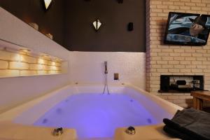 a large bath tub in a room with a tv at Noam Suites in Bruchim Qela' Alon