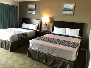 a hotel room with two beds and a lamp at Knights Inn Kamloops in Kamloops