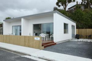 a small white house with a wooden fence at Seascape Accommodation in Kaka Point