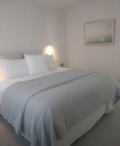 a large bed with white sheets and pillows at Seascape Accommodation in Kaka Point