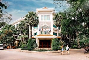 two people walking in front of a building at Angkor Holiday Hotel in Siem Reap