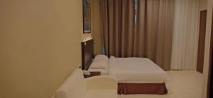 a hotel room with two beds and a window at Hotel Desaru Penawar in Desaru
