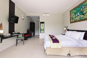 a bedroom with a large bed and a desk at Kebun Villas & Resort in Senggigi