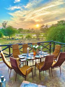 a table and chairs on a balcony with the sunset at Kruger River View in Marloth Park