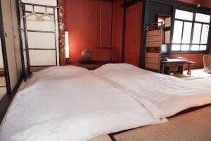 1 cama blanca grande en una habitación con paredes rojas en 一棟貸ゲストハウス 傾㐂屋 Kabukiya, en Hiroshima
