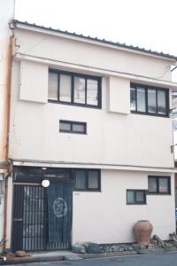 een wit gebouw met zwarte ramen en een deur bij 一棟貸ゲストハウス 傾㐂屋 Kabukiya in Hiroshima