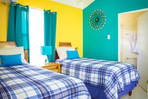 two beds in a room with yellow and blue at Ocho Rios Premier 2 Bedroom Villa at Drax Hall in Mammee Bay