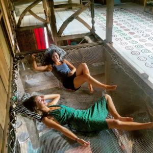 two women laying on the floor in a cage at The Rabbit Tree Hostel in Gili Meno