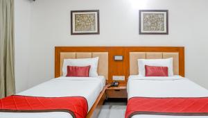 two beds in a hotel room with red pillows at The Altruist Business Hotel Navi Mumbai-1 in Navi Mumbai