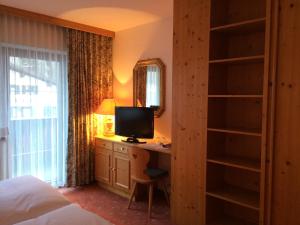 a bedroom with a desk with a computer and a television at Hotel Garni Senn in Sankt Anton am Arlberg