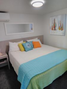 una cama con almohadas coloridas en una habitación en Harbourside Getaway, en One Tree Point