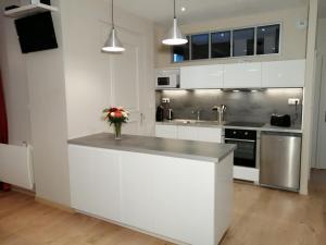 a white kitchen with a counter with a vase of flowers on it at Gite Côté Cour Colmar in Colmar