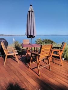 a table with an umbrella and chairs on a deck at Harbourside Getaway in One Tree Point