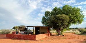un piccolo edificio con un camion davanti a un albero di Kalahari Anib Campsite a Hardap