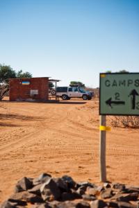 a green sign in the middle of a dirt road at Kalahari Anib Campsite in Hardap