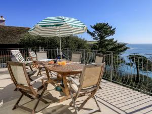 a table and chairs with an umbrella on a deck at Courtenay Villa in Salcombe