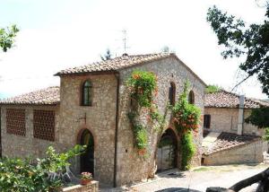 an old stone building with flowers on it at Fattoria di Mugnano in Colle di Val d'Elsa