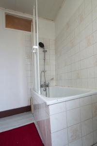 La salle de bains est pourvue d'une baignoire et d'un tapis rouge. dans l'établissement T1 situé à 100 m des thermes, à Aix-les-Bains