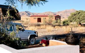 a truck parked next to a house in a field at Namib Desert Campsite in Solitaire