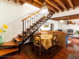 a dining room with a table and a spiral staircase at Casa maria la conejera in Nigüelas