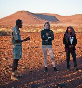 a group of three people standing in the desert at Palmwag Campsite in Palm