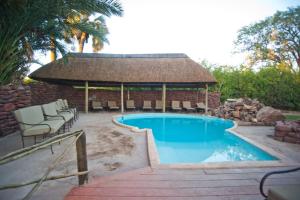 una piscina con cenador y sillas en Palmwag Campsite, en Palm