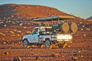 a white truck driving down a dirt road at Palmwag Campsite in Palm