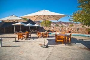 un gruppo di tavoli e sedie con ombrelloni accanto alla piscina di Omarunga Epupa-Falls Campsite a Epupa