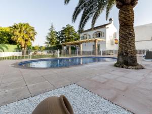 a swimming pool with a palm tree and a house at Venta del alamo in Dúrcal