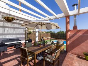 a patio with a wooden table and an umbrella at Villa flor in Padul