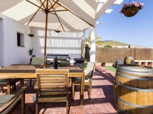 un patio con una mesa, una sombrilla y un barril en Villa flor, en El Padul