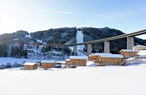 a snow covered town with a mountain and a bridge at Bergeralm Chalets by ALPS RESORTS in Steinach am Brenner