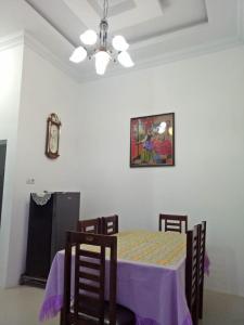 uma sala de jantar com mesa e cadeiras e um relógio em Villa SINGGALANG Syariah em Padangluar