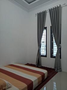 um quarto com 2 camas e 2 janelas em Villa SINGGALANG Syariah em Padangluar