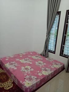a pink bed in a room with two windows at Villa SINGGALANG Syariah in Padangluar