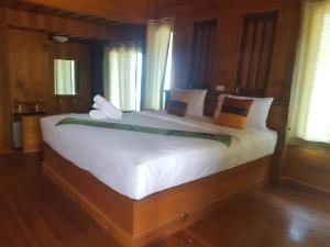 een groot wit bed in een kamer met ramen bij Phuphat Beach in Khanom