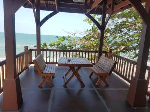 Una mesa y dos sillas en un porche con la playa en Phuphat Beach en Khanom