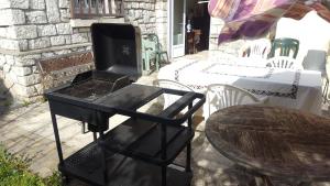 - un barbecue noir installé sur une terrasse avec une table dans l'établissement Apakabar Homestay - ambiance balinaise, parking privé, Netflix,, à La Rochette