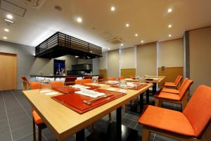 een grote eetkamer met oranje stoelen en tafels bij T Hotel Ryuoo in Shimotakai