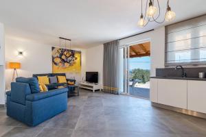 Villa Charm في تكون: غرفة معيشة مع أريكة زرقاء ومطبخ