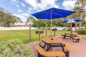 two picnic tables with blue umbrellas and a grill at Howard Johnson by Wyndham Lakeland in Lakeland