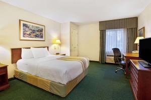 a hotel room with a bed and a desk and a television at La Quinta Inn by Wyndham Detroit Canton in Canton
