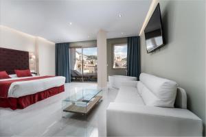 a hotel room with a bed and a living room at Los Arcos in Nerja