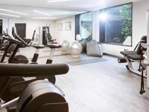 a gym with treadmills and exercise equipment in a room at Novotel Basel City in Basel